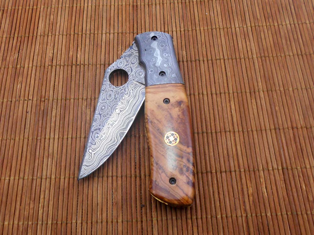 7.5" flat scale folding knife, Damascus steel blade with finger hole, Equipped with liner lock, Available in Wood & Horn scales, Leather sheath included
