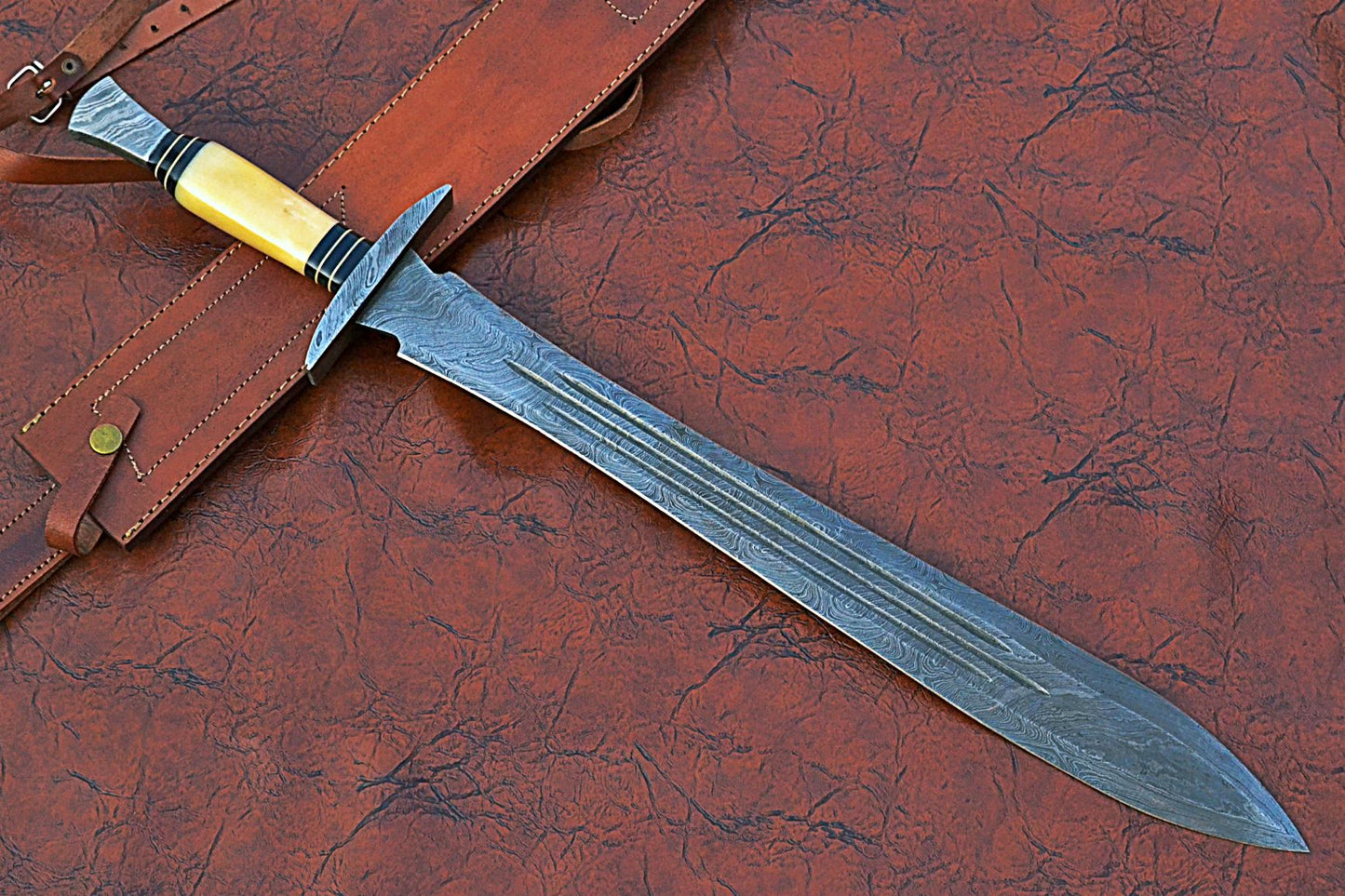 27" Long Sting Sword, 19" Long Hand Forged Damascus Steel Double Edge Blade with Triple Blood Groove, Brass Cross hilt Forward and Pommel, Damascus Guard & Pommel, Camel Bone Grip, Leather Scabbard