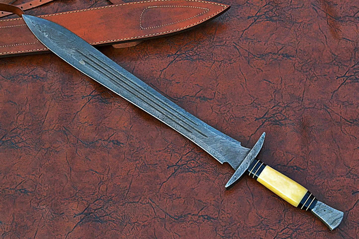 27" Long Sting Sword, 19" Long Hand Forged Damascus Steel Double Edge Blade with Triple Blood Groove, Brass Cross hilt Forward and Pommel, Damascus Guard & Pommel, Camel Bone Grip, Leather Scabbard