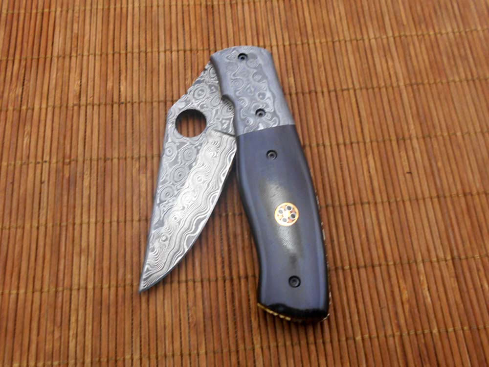 7.5" flat scale folding knife, Damascus steel blade with finger hole, Equipped with liner lock, Available in Wood & Horn scales, Leather sheath included
